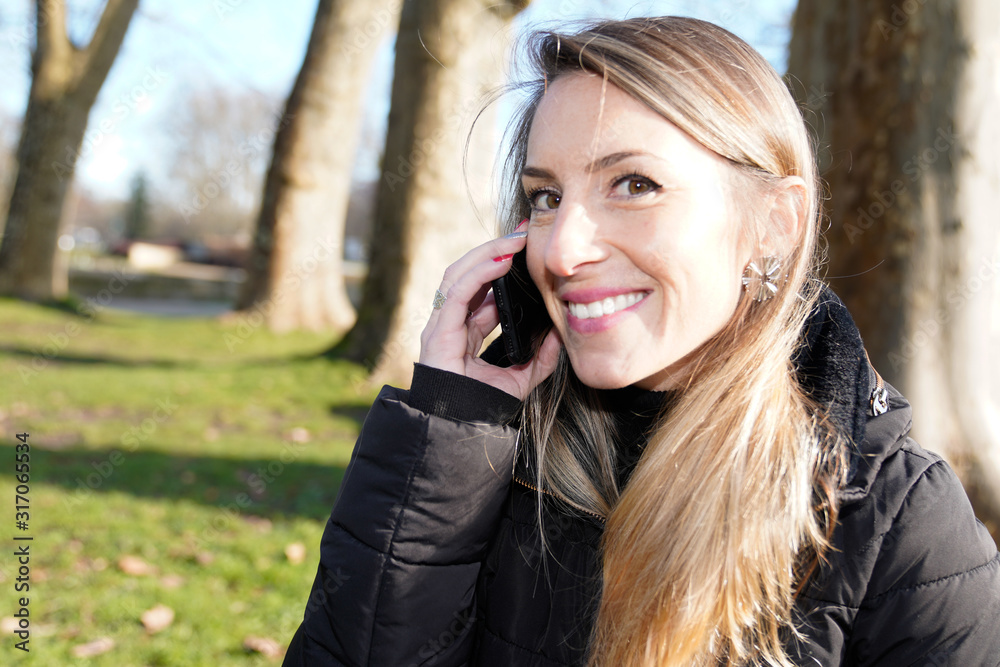 Happy blonde woman during a mobile phone call in autumn outdoors Happy blonde woman during a mobile phone call in autumn outdoors