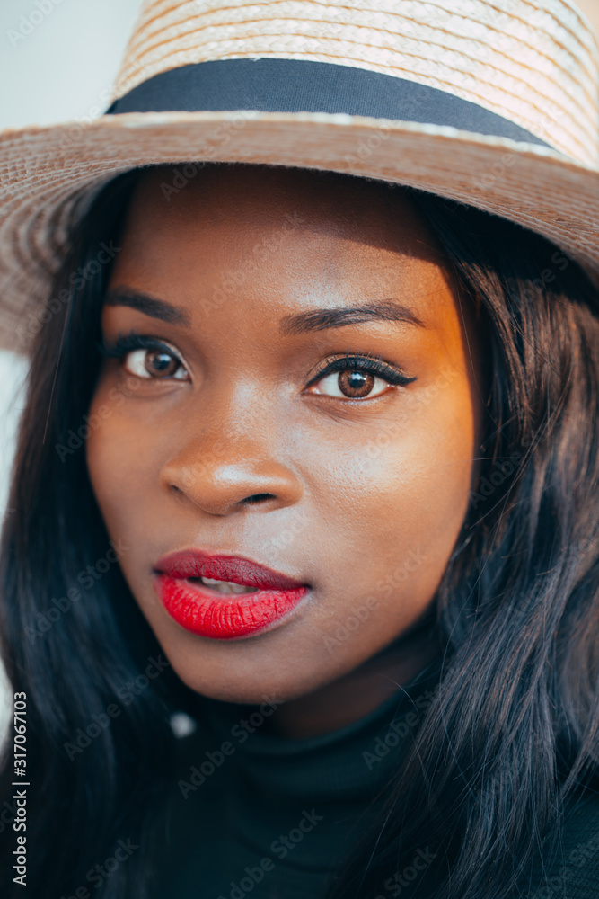 Beautiful young black african girl in a hat with a happy smile on the street in the rays of the setting autumn sun. close-up. Fashion colors Beautiful young black african girl in a hat with a happy smile on the street in the rays of the setting autumn sun. close-up. Fashion colors