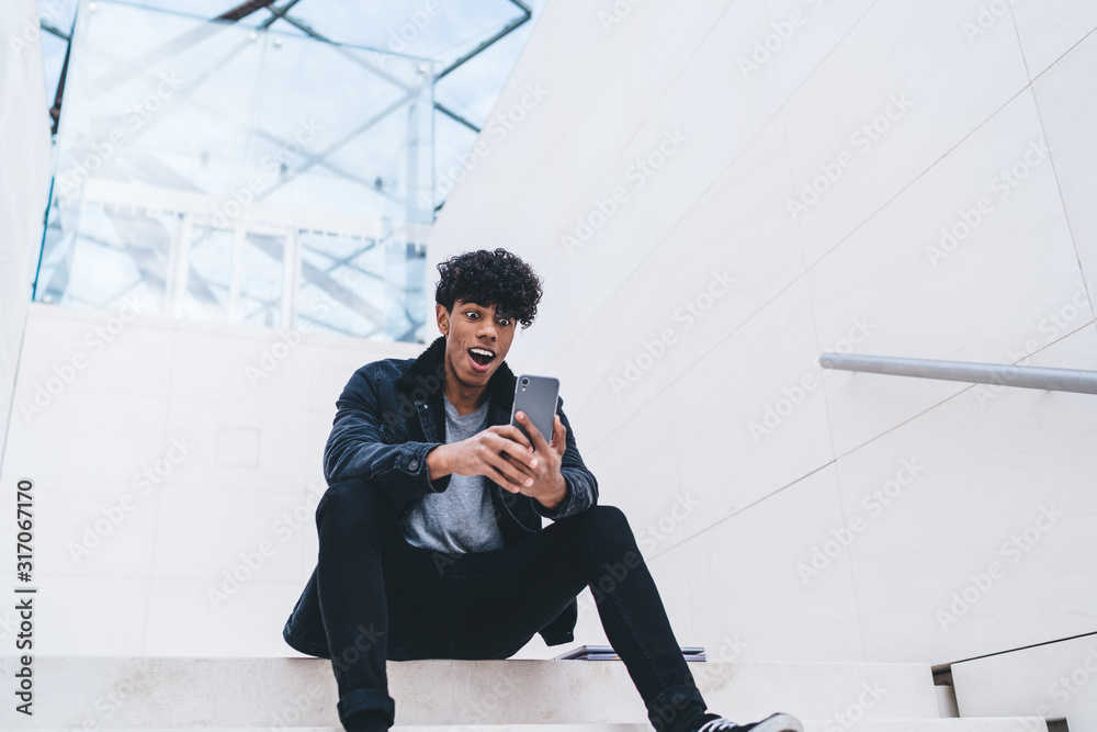 Surprised African American man using smartphone Surprised African American man using smartphone