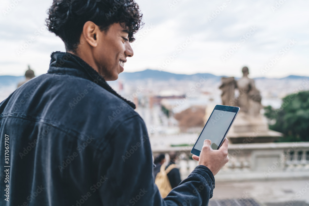Fototapeta premium Ethnic cheerful male using tablet on street