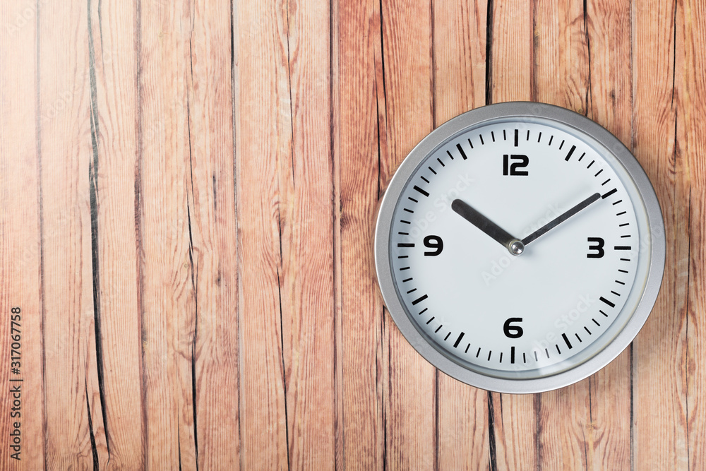 White wall clock with a yellow used hanging on the wall. Minimalist image of a wall clock on a wooden background with copy space White wall clock with a yellow used hanging on the wall. Minimalist image of a wall clock on a wooden background with copy space