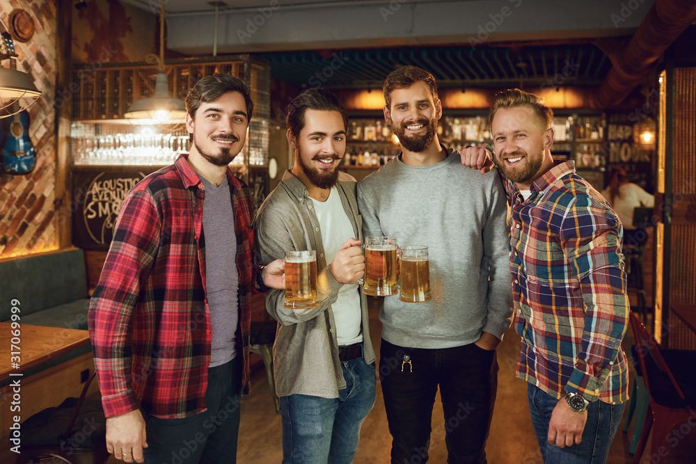 Group of male friends drink beer at a party in a bar.