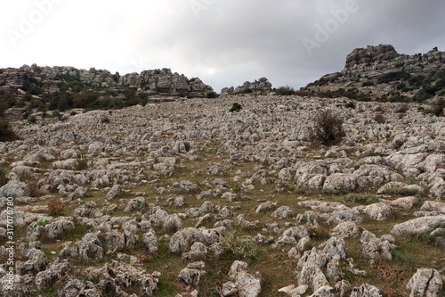 View on a hill being covered with tons of fractured rock pieces surrounded by larger limestone rocks in the impressive rock landscape of El Torcal de Antequera, Spain, Europe