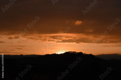 Beautiful orange sunset, the sun is hidden behind the mountains and trees