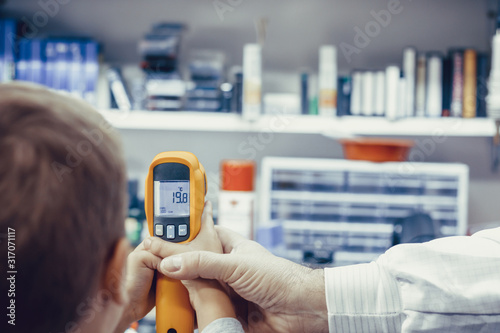 Close-up of boy measuring temperature with infrared thermometer.