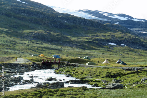 Camping tents near a rapid river in the still snow covered mountains of the Sognevellsweg / Sognefjellsvegen or Sognefjellsveien, Auerlandfjellet, Norway, Europe photo