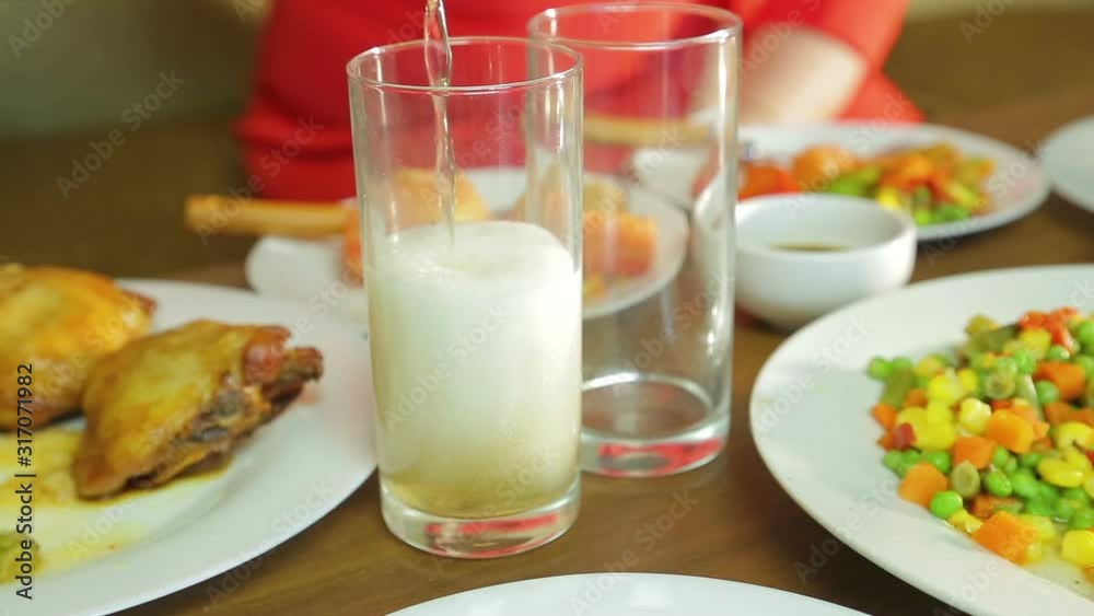 Foamy light beer from a bottle is poured into a transparent glass Foamy light beer from a bottle is poured into a transparent glass