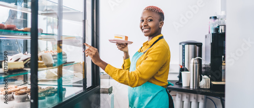 Fotografi Shop assistant pointing at cake in pastry shop