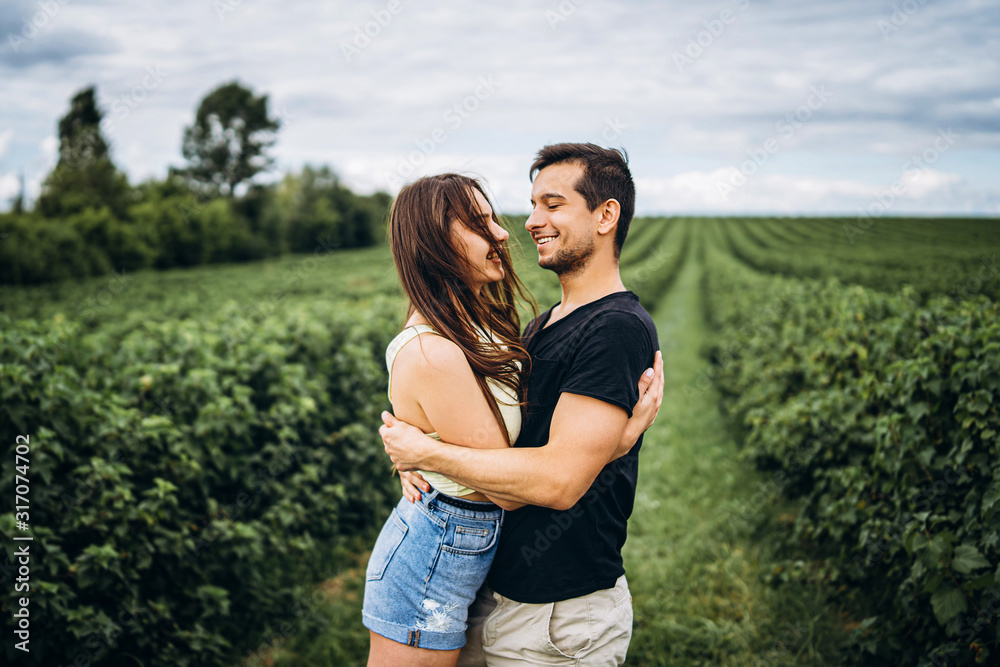 A tender loving couple walking in a field of currant. Man whirls woman in her arms. Love story A tender loving couple walking in a field of currant. Man whirls woman in her arms. Love story
