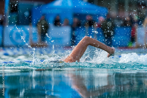 Woman swimming freestyle in an outdoor pool at an ice swimming event © DZiegler