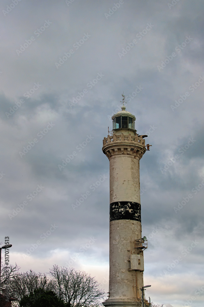 View of old, stone brick lighthouse under a dark, stormy sky. View from below. Winter landscape in Istanbul, Turkey
