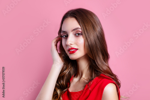 beautiful young woman in a red dress and with red lips on pink background