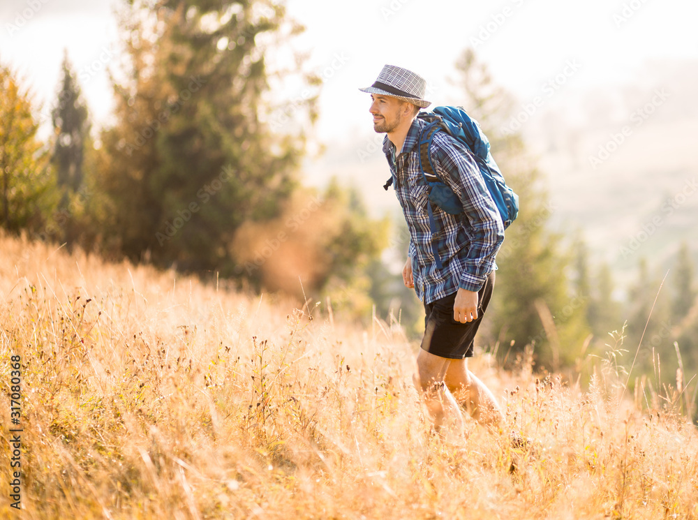 Bearded tourist man in hat with backpack hiking in mountains forest. Caucasian male hiker outdoors Bearded tourist man in hat with backpack hiking in mountains forest. Caucasian male hiker outdoors