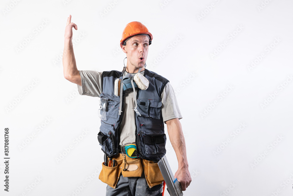The builder shows up in surprise. In work clothes and hard hat. On a light gray background. The builder shows up in surprise. In work clothes and hard hat. On a light gray background.