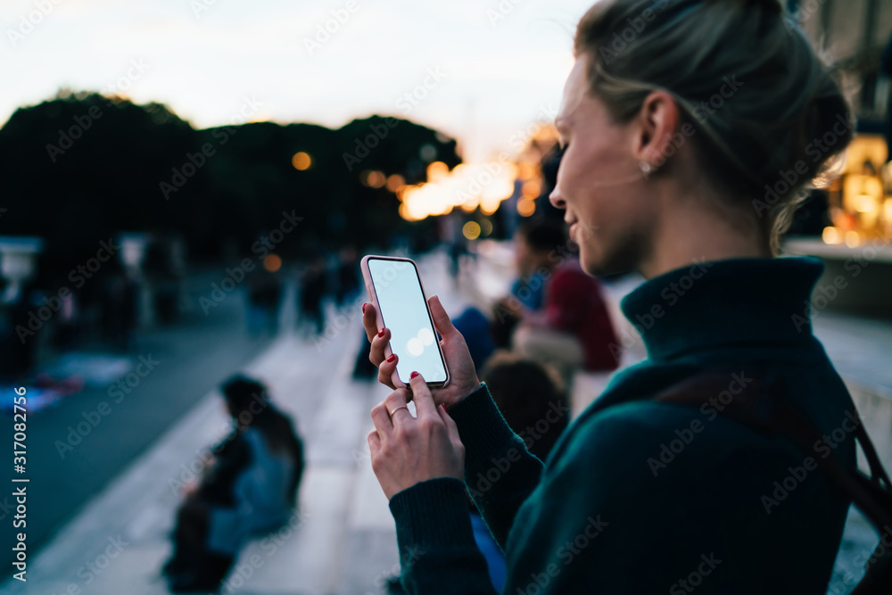 Glad female tourist looking on smartphone during walk around city - obrazy, fototapety, plakaty 