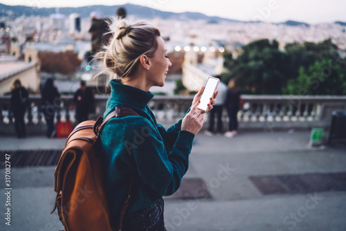Joyful female tourist with smartphone exploring city photo