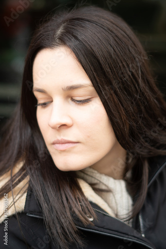 Downcast eyes. Close-up portrait of an attractive young brunette woman looking down