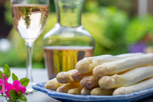 Fresh raw peeled white asparagus vegetables ready to cook and rose wine in spring garden