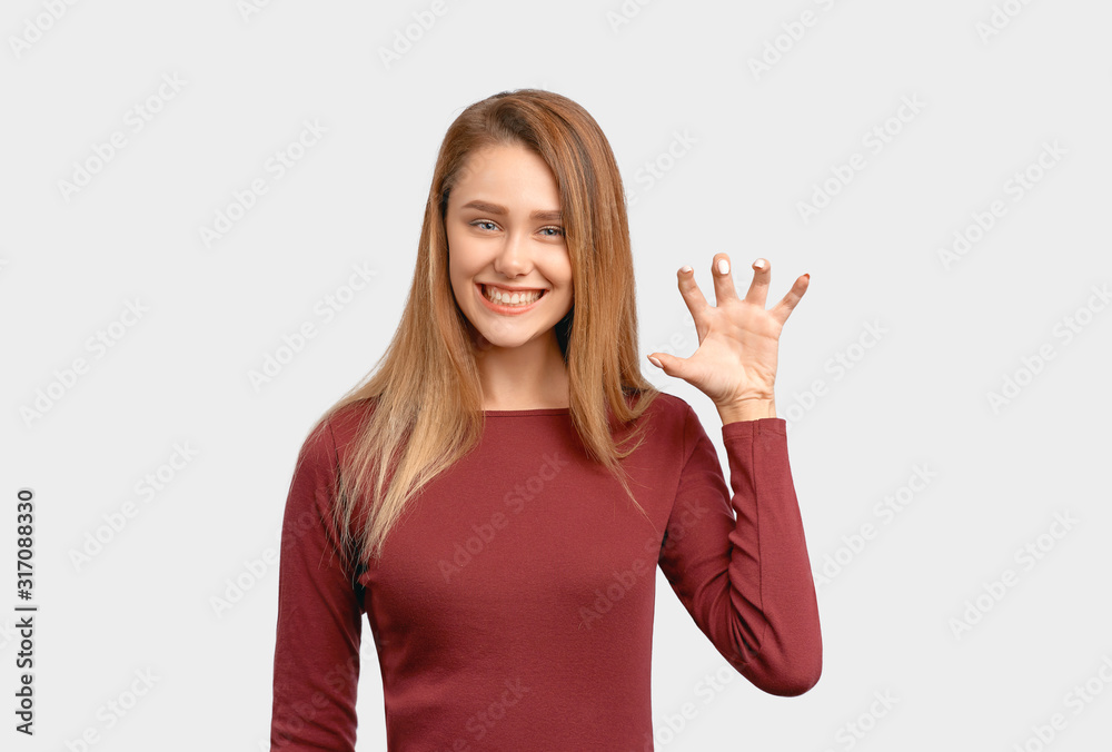 Portrait of cute girl, showing teeth like while roaring, raising hand like paw while pretending lioness, looking flirtatiously at camera. Beautiful young woman isolated on white background in Studio Portrait of cute girl, showing teeth like while roaring, raising hand like paw while pretending lioness, looking flirtatiously at camera. Beautiful young woman isolated on white background in Studio