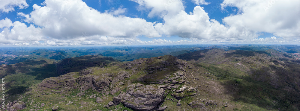 Aerial super wide panorama of the Itacolomi mountain top ridge in Ouro Preto, Brazil, with trails leading to and from viewpoint with levitating sticking out rocks