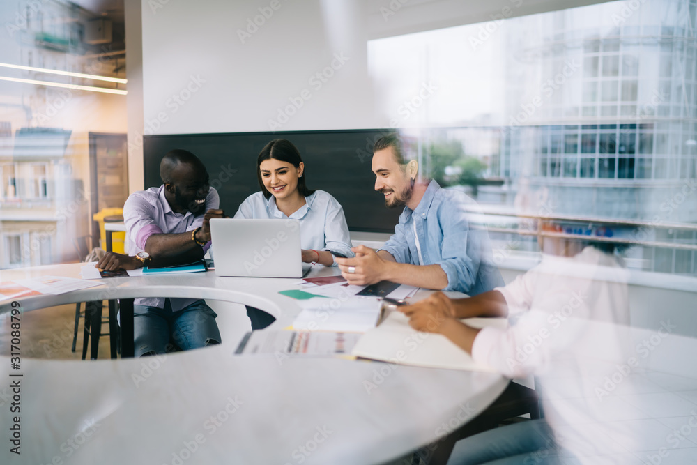 Multiethnic workers discussing ideas and smiling in light office Multiethnic workers discussing ideas and smiling in light office
