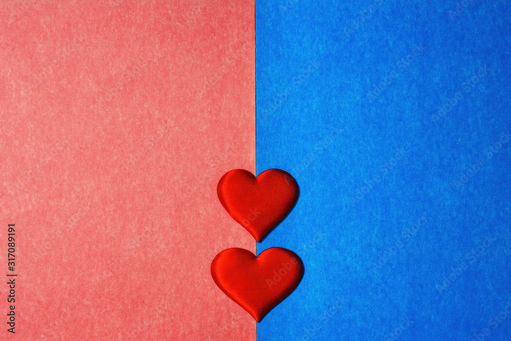 Top view of two red hearts in center of blue and pink cardboard background. Copy space for text, Valentines Day concept.