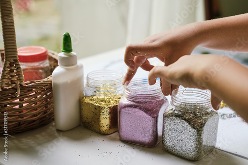 Child's hands taking up containers of glitter for making art work