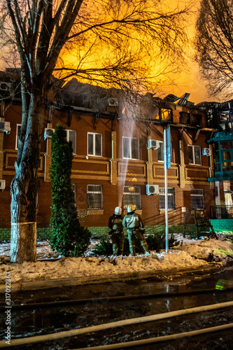 Firefighters extinguish a burning house with a fire-pump in the dark, Burning building in Samara, Russia, selective focus