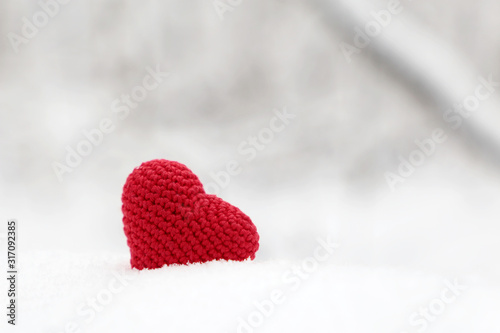 Valentine heart in winter forest. Red knitted heart  symbol of romantic love in the snow  concept of Valentine s day