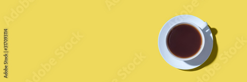 A cup of black coffee or tea on a yellow background. Minimal concept. Flat la...