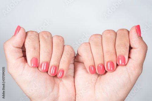 Closeup top view of two female hands with fresh bright gel polished manicure of fingernails isolated on white background. photo