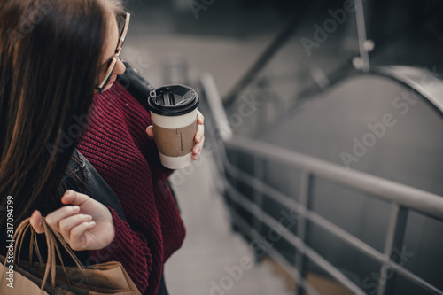 Young pretty woman blogger with smartphone, cup of coffee and shopping bags in city mall