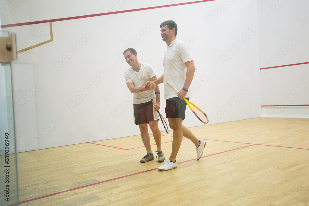 Squash players shaking hands after the game on squash court/Two men playing match of squash Squash players shaking hands after the game on squash court/Two men playing match of squash