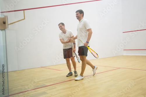 Squash players shaking hands after the game on squash court/Two men playing match of squash