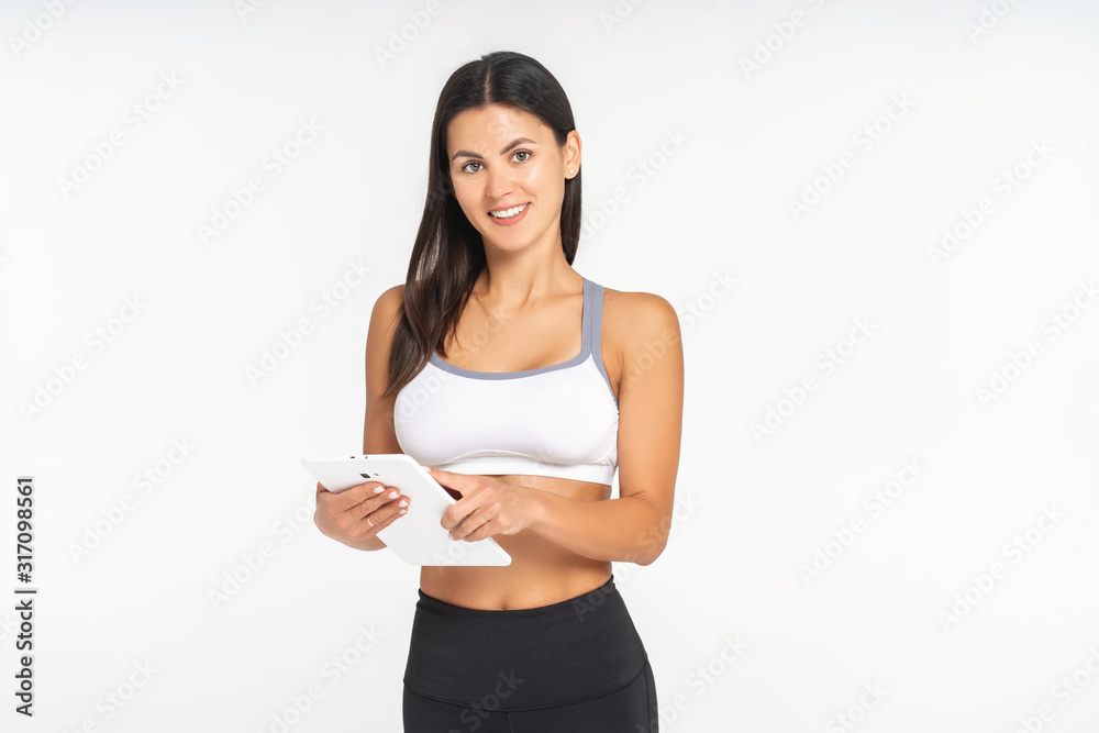 athlete girl on a white background is watching a sports application in a tablet athlete girl on a white background is watching a sports application in a tablet