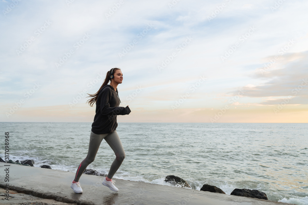 runner in sportswear on the background of the sea and sunset