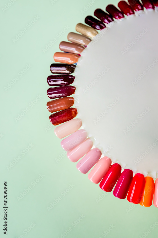Obraz premium Nail polish in different fashion color. Colorful cats eye 3D nail lacquer in tips and mock-up blank bottle isolated on pastel background.healthy nails.Selective focus. Copy space.Finger nail art