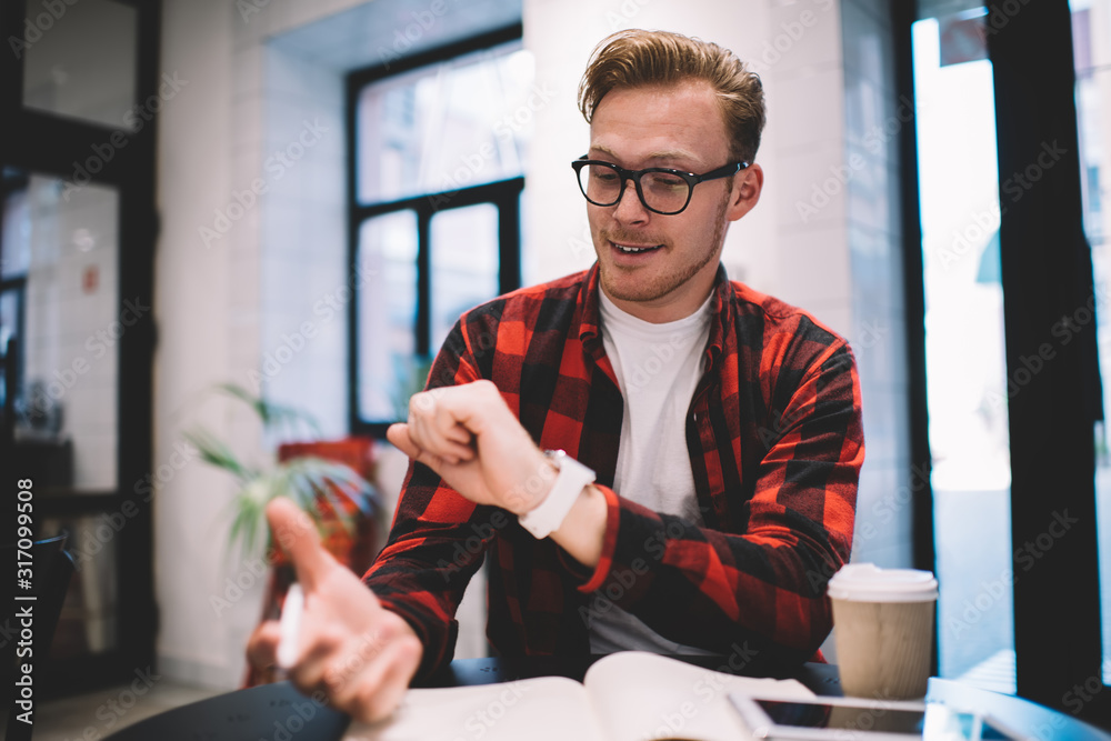 Optimistic guy checking time in coffee bar Optimistic guy checking time in coffee bar