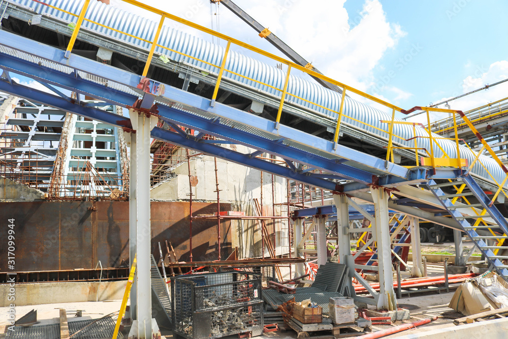 Metal iron structures, industrial production with a conveyor, pipes, railings and pipelines at the production of an oil refining petrochemical plant Metal iron structures, industrial production with a conveyor, pipes, railings and pipelines at the production of an oil refining petrochemical plant
