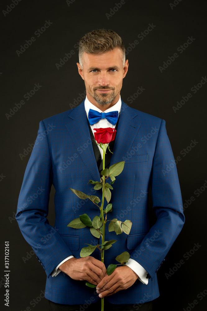 Floristics for ceremonies. Rich groom at wedding. handsome man in tuxedo with bowtie. red rose symbol of passion and desire. valentine man devotion. tuxedo is best. sexy man at formal reception Floristics for ceremonies. Rich groom at wedding. handsome man in tuxedo with bowtie. red rose symbol of passion and desire. valentine man devotion. tuxedo is best. sexy man at formal reception