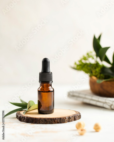 Skin care. Moisturizing serum on a wooden stand, green leaves on a light background. There is a place for text.