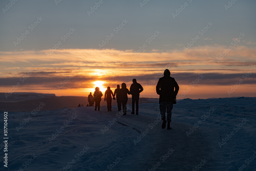 Silhouette of group of tourists walking through snow at sunset in Iceland Silhouette of group of tourists walking through snow at sunset in Iceland