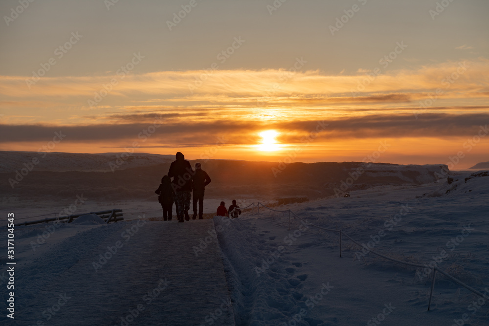 Silhouette of group of tourists walking through snow at sunset in Iceland Silhouette of group of tourists walking through snow at sunset in Iceland