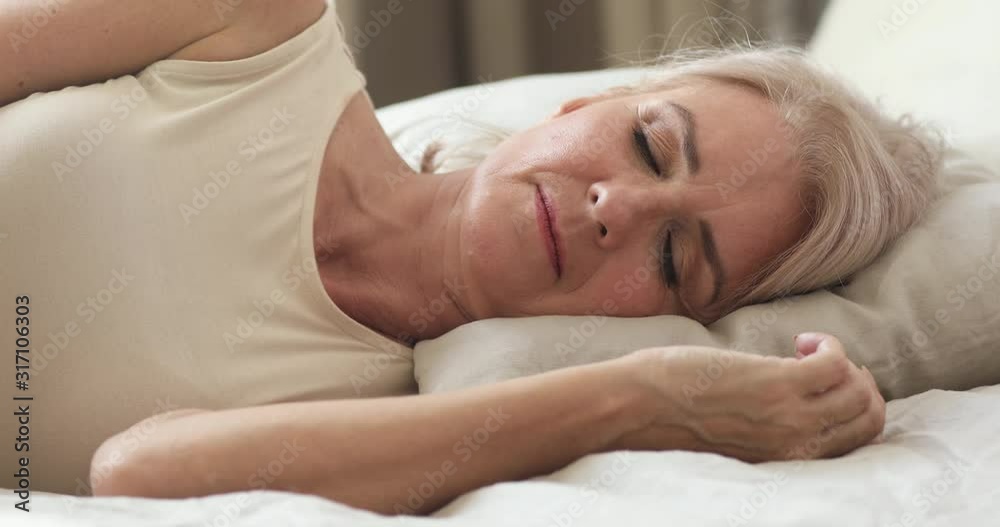Calm serene mature woman resting sleeping well in comfortable bed Calm serene mature woman resting sleeping well in comfortable bed