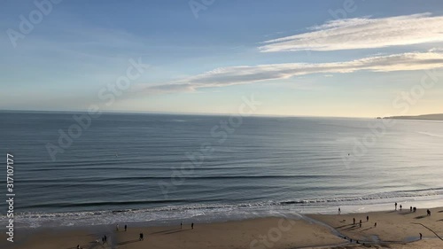 Panning shot of people walking onto Bournemouth beach close to sunset  photo