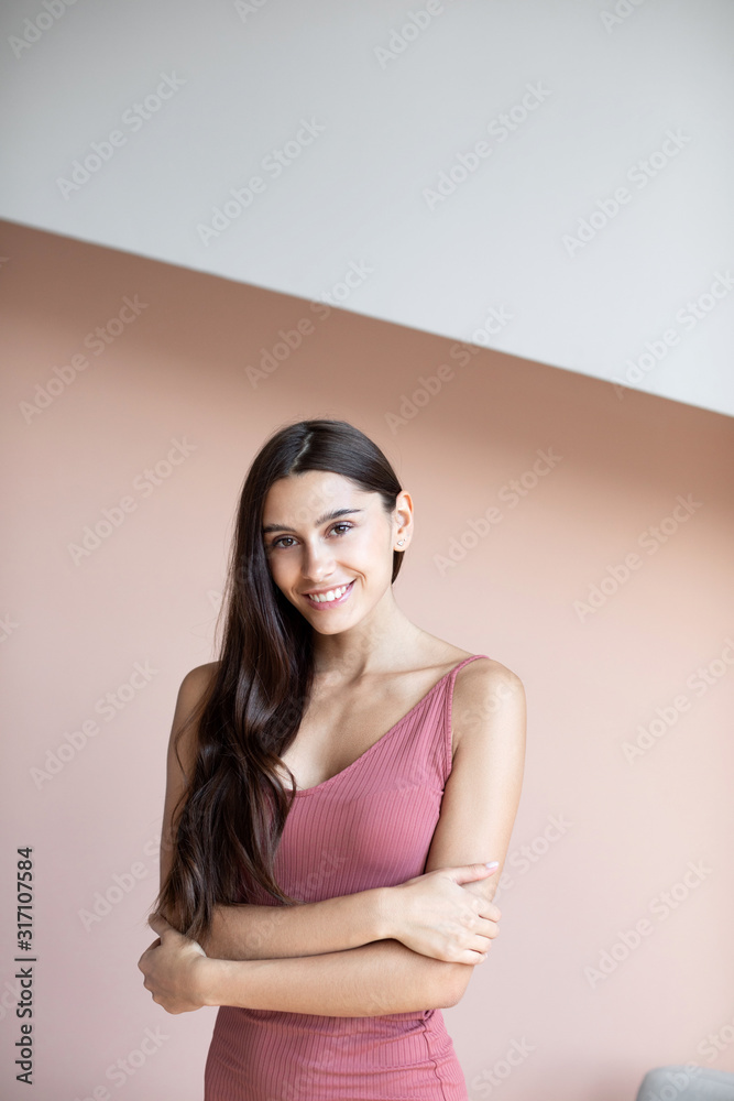 Beautiful woman with long hair is smiling indoors on wall background. Beautiful woman with long hair is smiling indoors on wall background.