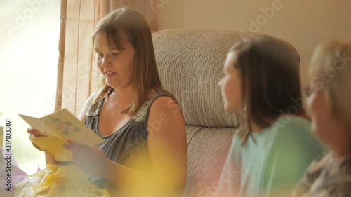 Pregnant woman reading card and laughing at her baby shower party with her family and friends 
