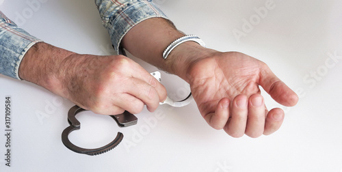The criminal is released from prison.The acquittal was handed down to an innocent defendant. Hands unbuckling handcuffs. Open handcuffs on the male hands of the arrested person. photo