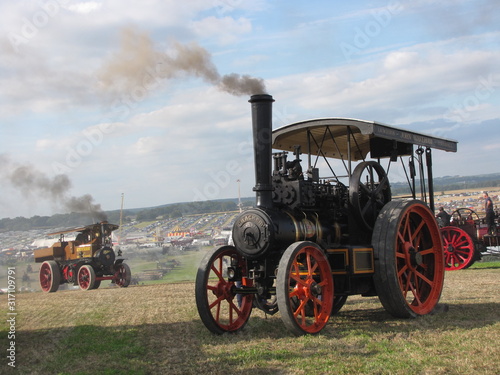 Carta da parati two historical steam engines are driving at a at a hilly field with big smoke pl