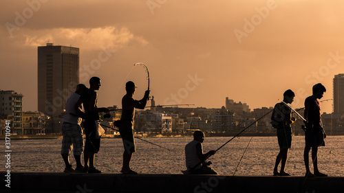 Photography Men fishing from the Malecon wall at dusk